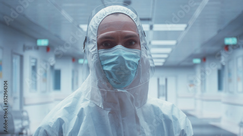 Portrait of Caucasian female doctor posing in a protective suit and face shield in an empty hospitall hallway photo