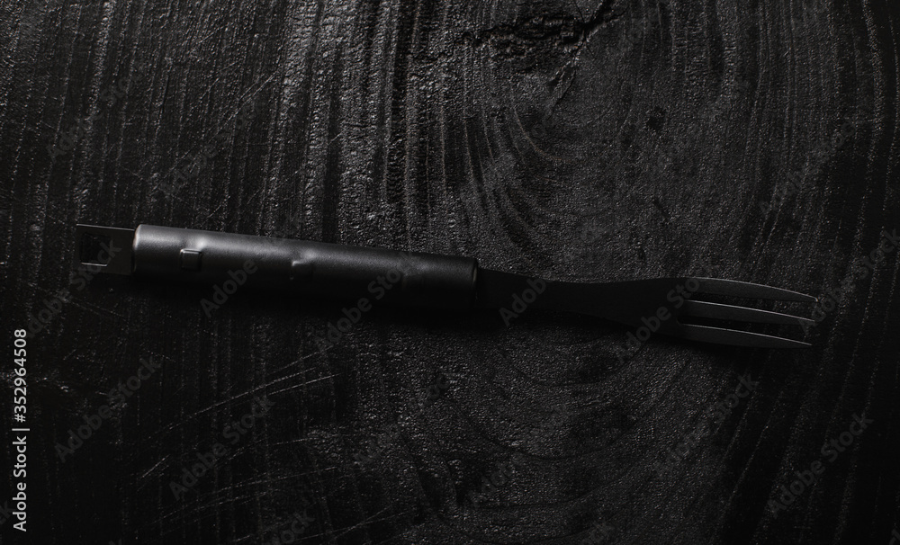 Black mate fork on a pice of black wood