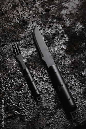 Obraz na płótnie Knife and for on pice of black wood and black texturated background. w salonie