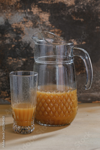 Obraz na płótnie Pitcher with glass and orange juice on photographed with natural light on brown textured background. w salonie