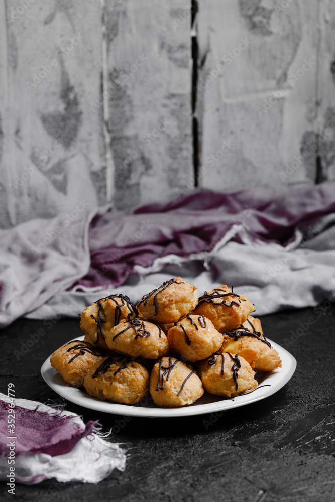 Delicious profiteroles on black textured background with a creative decoration.