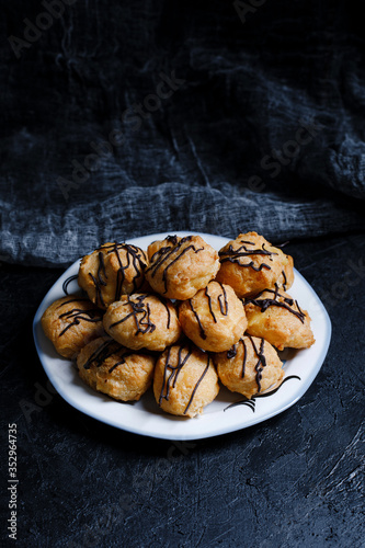 Obraz na płótnie Delicious profiteroles on black textured background with a creative decoration. w salonie