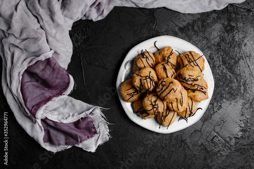 Obraz na płótnie Delicious profiteroles on black textured background with a creative decoration. w salonie