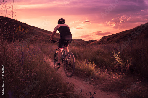 Tableau sur toile hombre haciendo deporte con bicicleta de montaña al atardecer