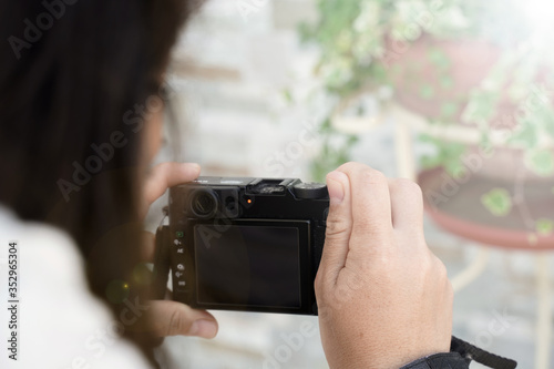 girl with vintage camera makes a shot at a plant, selective focus, flare in the upper left corner, ideal for concept, copyspace. Photographer shot from behind 