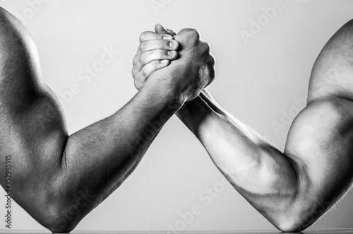 Muscular men measuring forces, arms. Hand wrestling, compete. Hands or arms of man. Muscular hand. Two men arm wrestling. Rivalry, closeup of male arm wrestling. Black and white