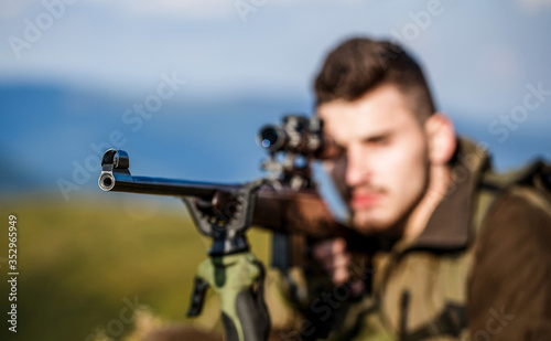 Hunter with hunting gun and hunting form to hunt. Hunter is aiming. The man is on the hunt. Hunt hunting rifle. Hunter man. Shooter sighting in the target. Hunting period. Male with a gun. Close up