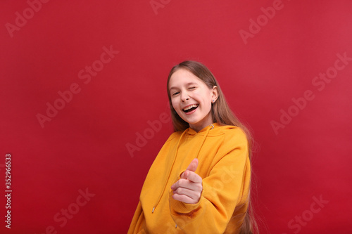 Dancing girl in a sweater on a red background. © Evgenia