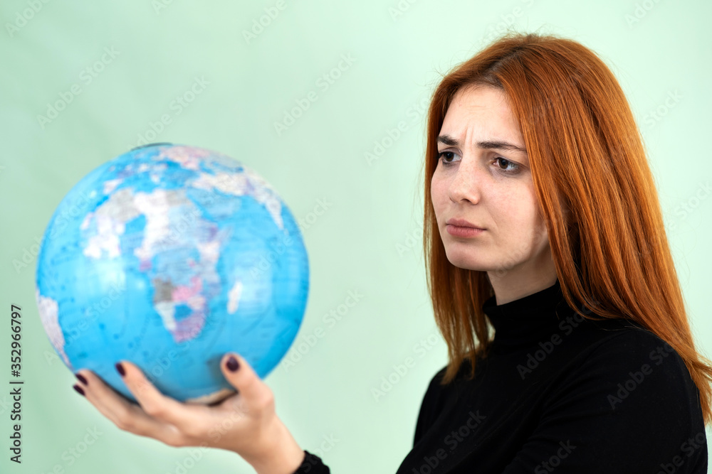 Portrait of a sad worried young woman holding geographic globe of the world in her hands. Travel destination and planet protection concept. Portrait of a sad worried young woman holding geographic globe of the world in her hands. Travel destination and planet protection concept.