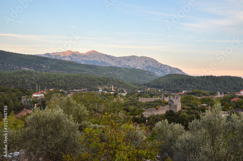 View of the ruins of the ancient Roman Kadrema castle located in the Gedelme village at sunset and mountain ridge on background. Lycian way, Turkey