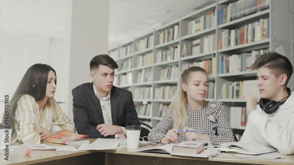 College students working together preparing for exams while sitting at table at university library College students working together preparing for exams while sitting at table at university library
