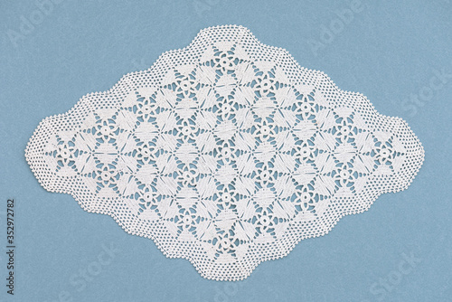 White handmade lace isolated on the blue background. Crocheted accessory. Crafts and Hobbies for women. 