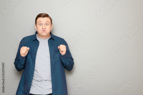 Portrait of excited man raising clenched fists in anticipation
