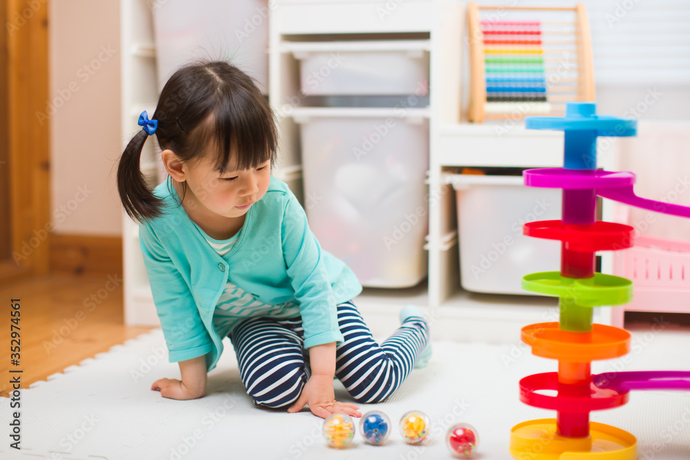 toddler girl play marble run game at home against white background toddler girl play marble run game at home against white background
