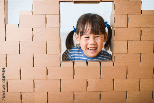 toddler girl use cardboard blocks to  buid  house at home photo