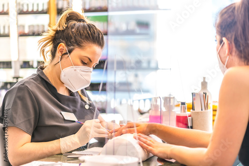 Manicure and pedicure salon worker with security measures and face masks at the reopening of the covid-19 pandemic. Coronavirus photo
