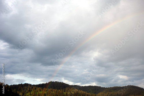 Bewölkter Himmel nach Wetterumbruch über Schwarzwald mit schönem Regenbogen