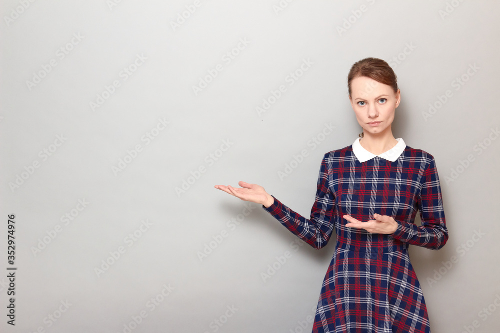 Portrait of serious girl pointing with both hands at copy space