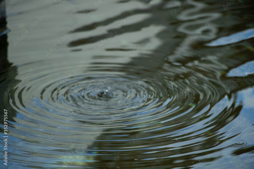 Wasser fließt aus dem Brunnen und es bilden sich Wasserwellen Wasser fließt aus dem Brunnen und es bilden sich Wasserwellen