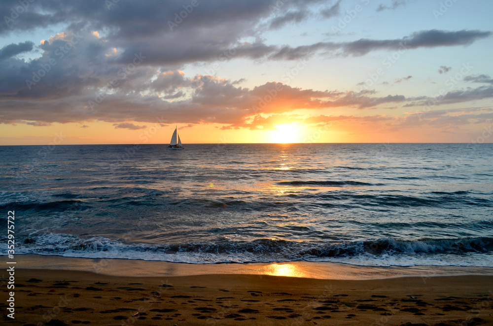 Sunset over the Caribbean Sea from Puerto Rico with sailboat in distance. Rincon, PR. Copy space. Background. Sunset over the Caribbean Sea from Puerto Rico with sailboat in distance. Rincon, PR. Copy space. Background.