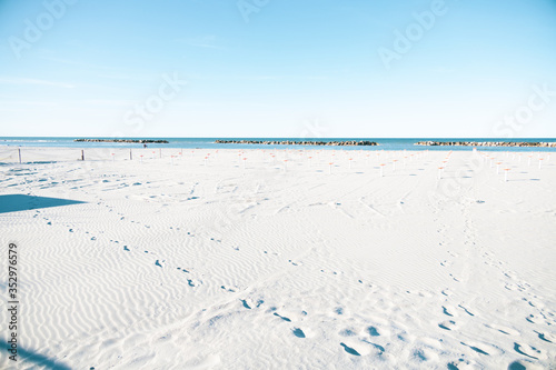 Fototapeta Naklejka Na Ścianę i Meble -  Slightly overexposed shot of a beach in the Italian Adriatic Riviera Romagnola area, noby around due to covid. Flat horizon, minimal and absence consepts. Desolation yet positivity.