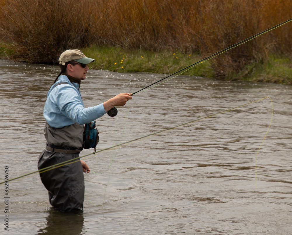 A man teaching a boy how to fly fish on a western trout stream. A man teaching a boy how to fly fish on a western trout stream.