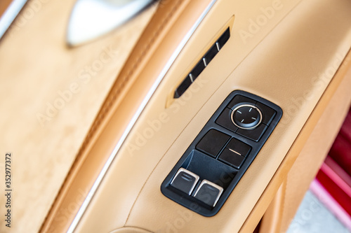 Beige car interior with black buttons on the door. Close-up. Horizontal orientation.