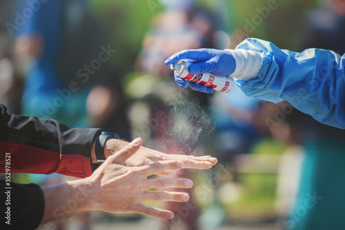 Close-up of a medic hand spraying disinfectant on a man's hands on the street. photo