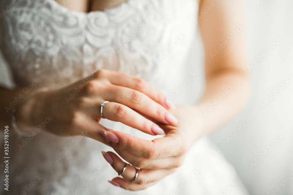 Beautiful luxury bride in elegant white dress holds wedding rings in the hands Beautiful luxury bride in elegant white dress holds wedding rings in the hands