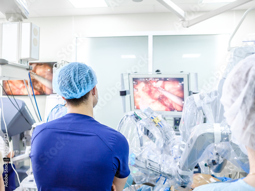 A group of surgeons in a medical uniform oversees medical equipment. The process of performing a surgical operation using a modern robotic surgical system.