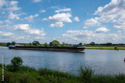 Summer morning - a dutch dike landscape at the river Maas with boat. Agricultural landscape.