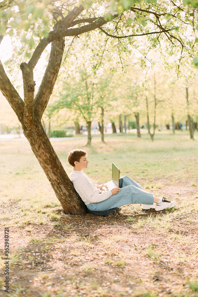 woman laptop park clearing sits near tree woman laptop park clearing sits near tree