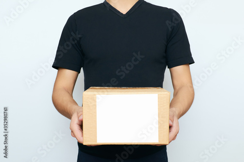 A person holding a box with copy space on a white background. The concept of online ordering, business purchasing, and courier delivery to your home