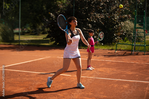 a mother and daughter playing tennis outdoors and having fun © kevin