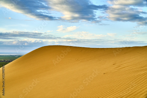 Yellow desert. Sand dunes. Blue sky and white clouds. Birds at sunset. Mountains of sand. The multi-colored sky. Feather clouds.