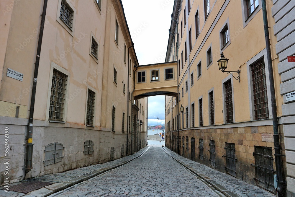 Stockholm / Sweden - 7 May 2020: Narrow alley with window bridge connecting buildings in gamla stan empty no people deserted