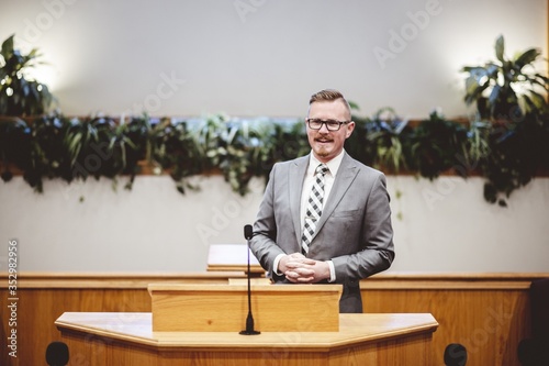 Male in a formal outfit preaching the Holy Bible from the tribune at the altar of the church
