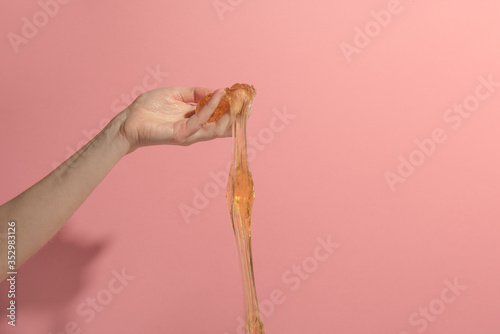 Fototapeta Naklejka Na Ścianę i Meble -  Sugar paste in hand on pink background. Concept epilation. Copy Space