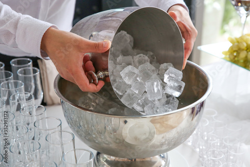 the waiter pours ice pieces to cool the bottles
