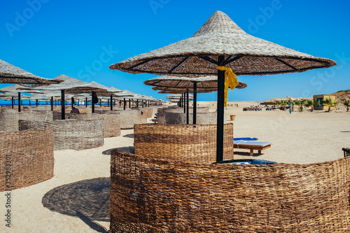 Empty beautiful clean beach with sunbeds and umbrellas, Egypt. Vacation concept. View of the beach with umbrellas and palm trees