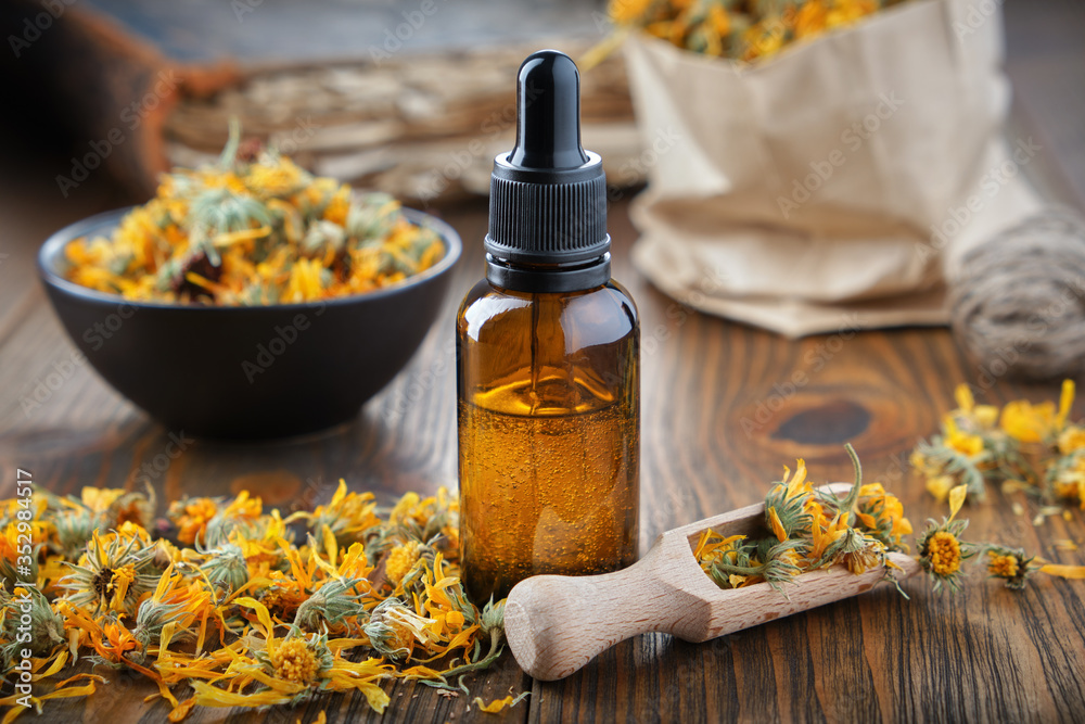 Dropper bottle of calendula essential oil, infusion or serum, healthy  marigold flowers in bowl and paper bag of dry calendula on background. foto  de Stock | Adobe Stock