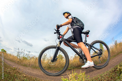 Fototapeta Naklejka Na Ścianę i Meble -  Beautiful girl cyclist with a bicycle on the nature. Healthy lifestyle and sport. Leisure and hobbies