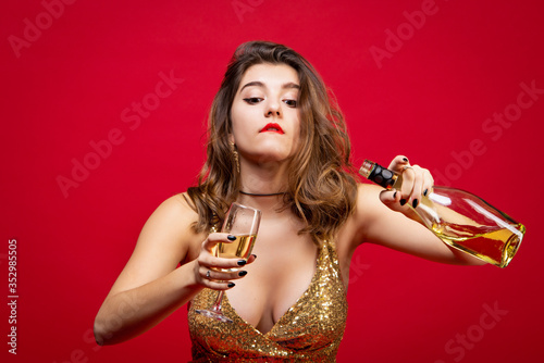 Sexy woman in gold dress with red lipstick pours champagne into a glass. Concept of a New Year holiday, Birthday party