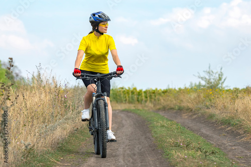 Beautiful girl in yellow riding a bike in nature. Sports and recreation. Hobbies and health.