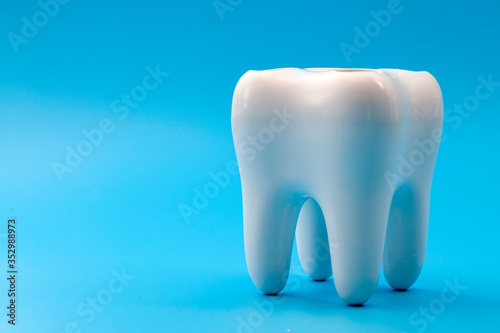 Dental hygiene  cosmetic dentistry and teeth cavity prevention concept with anatomical model of crown or corona of human tooth isolated on blue background with copy space