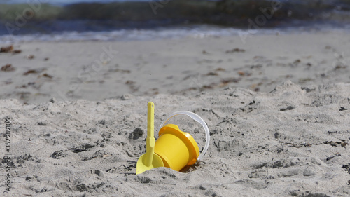 Bucket spade sandcastle Diggers toys on sandy beach with sea wave in UK