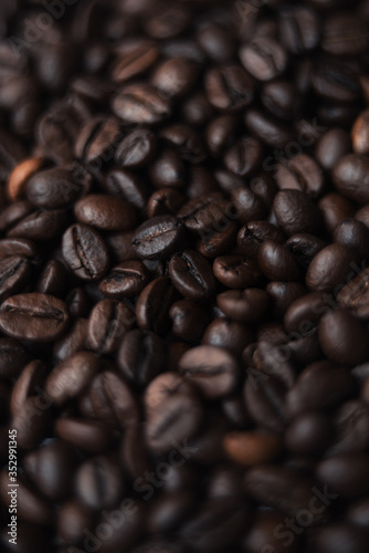 Coffee beans in blur with focuses in the middle. background for the desktop in the coffee industry, top view. dark roasted coffee.
