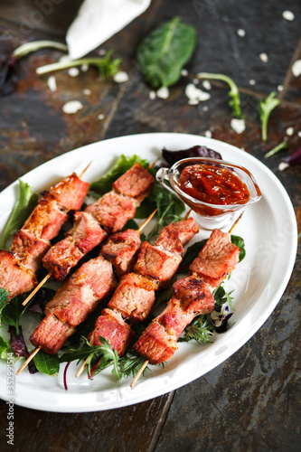 Pork skewers with sauce and herbs on a wooden skewer