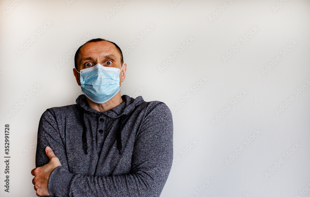 Expression of fear. Young man wearing a protective medicine mask isolated on white background.