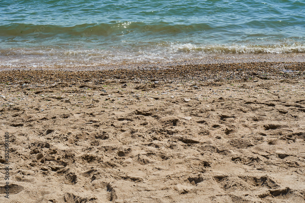 Sandy beach. Footprints of people on the sand near the water of the sea and ocean. Sunny day by the water without people. Sandy beach. Footprints of people on the sand near the water of the sea and ocean. Sunny day by the water without people.